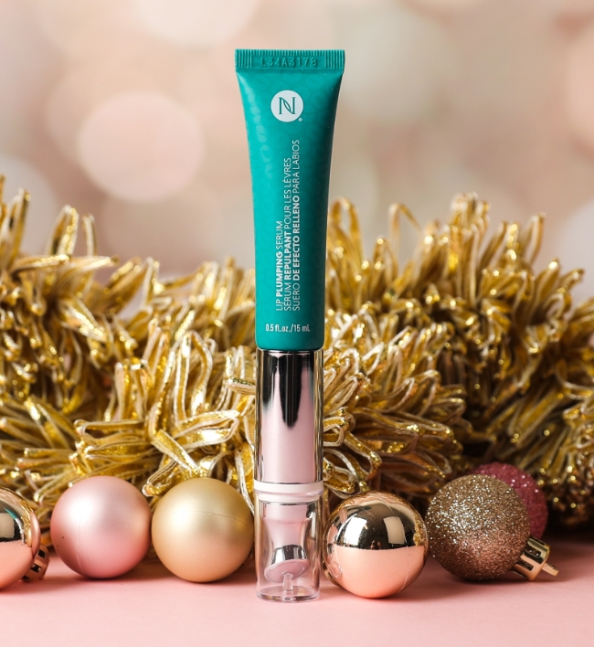 Lip Plumping Serum in front of wreath and ornaments